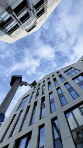 Mycie elewacji z podnośnika koszowego w ścisłej zabudowie w centrum Gdańska podczas prac wysokościowych przy budynku.
